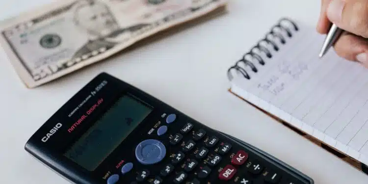 Crop unrecognizable accountant counting savings using notebook and calculator