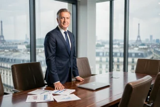 PDG en costume sombre debout en tête d'une salle de conseil d'administration avec vue sur Paris, illustrant les hauts salaires des dirigeants du CAC 40